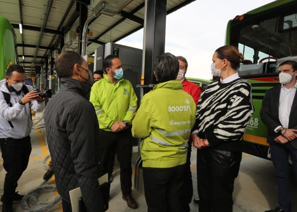 People talking near an electric bus