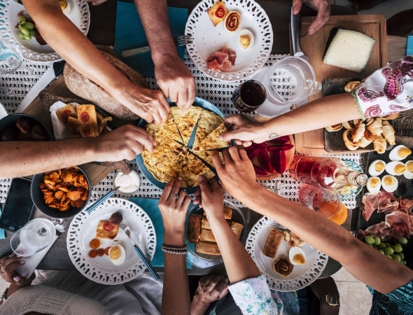 Someone’s hands at a table taking a piece of focaccia bread