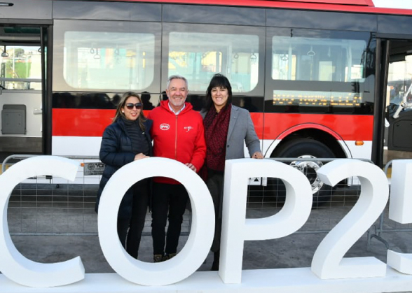 Tre persone davanti un autobus elettrico