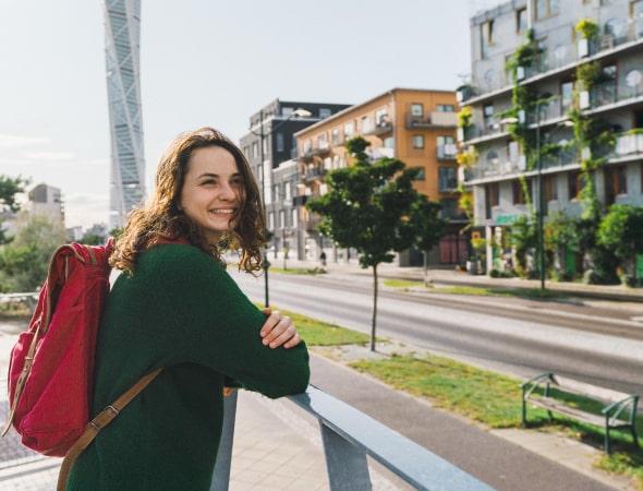 Chica con mochila apoyada en una barandilla