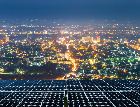 Paneles solares en primer plano con la ciudad al fondo